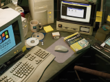 PC de escritorio noventosa con monitor CRT, diskettes y cajas de software sobre una mesa